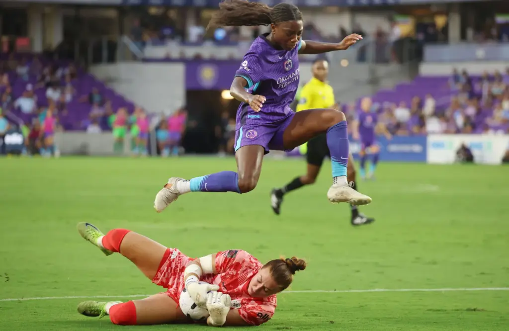 Orlando player Nicole Payne (top) leaps over Louisville goalkeeper Jordyn...
