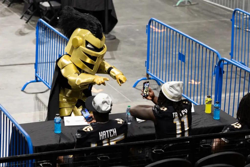 Knightro dances while Knightâs Football Player Ken Talley takes a...