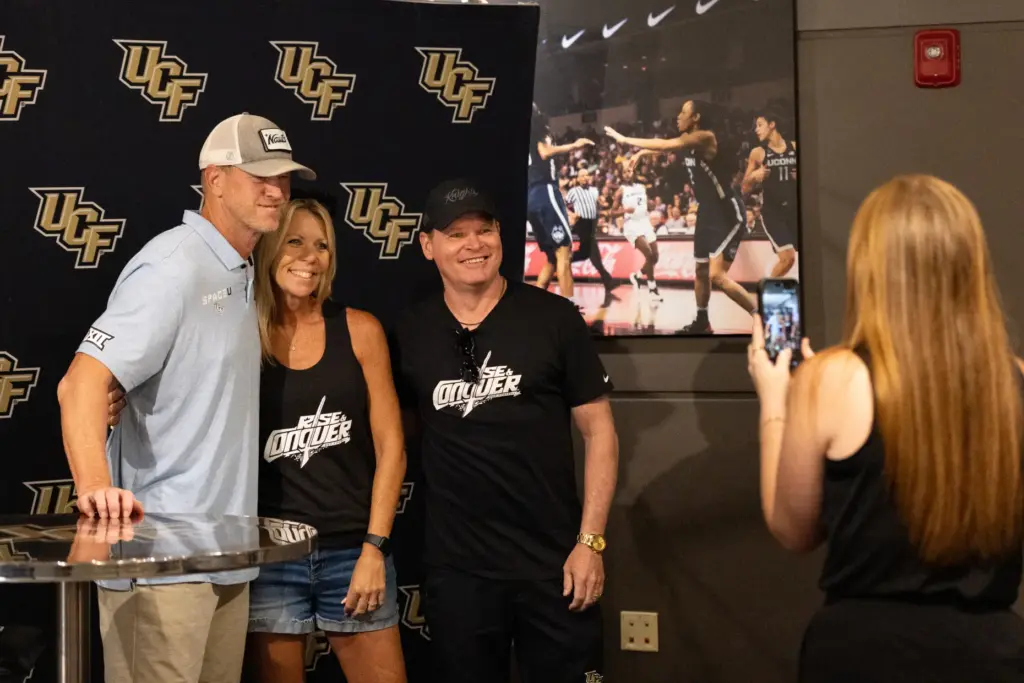 Knightâs Football Coach Scott Frost, left, takes a photo with...