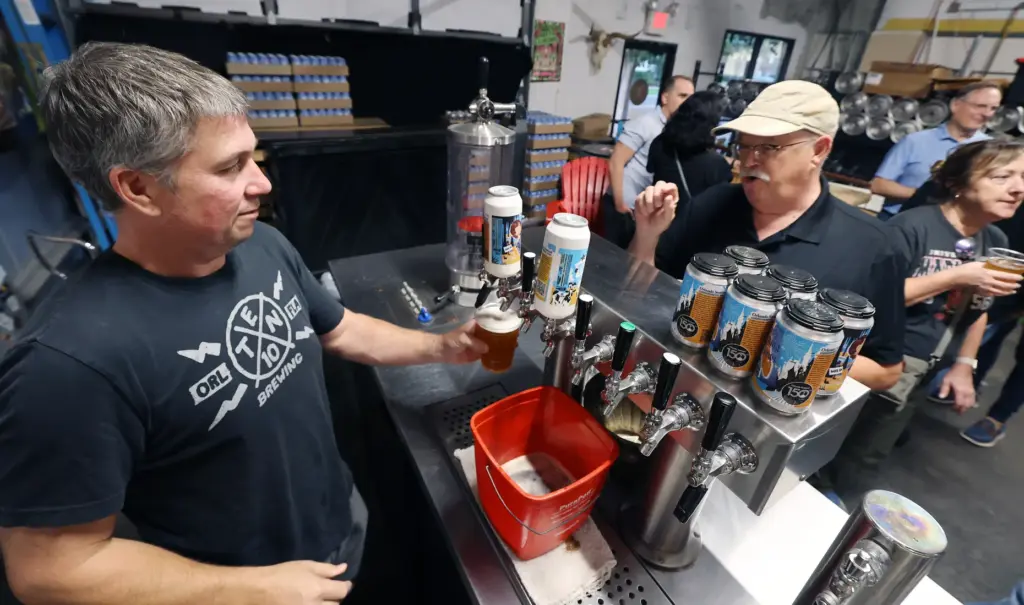 Brewery owner Mike Wallace , left, pulls a draft of...
