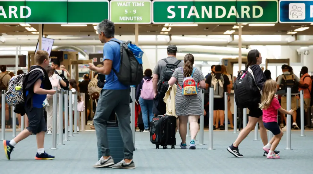 Travelers walk past the security check at the Orlando International...