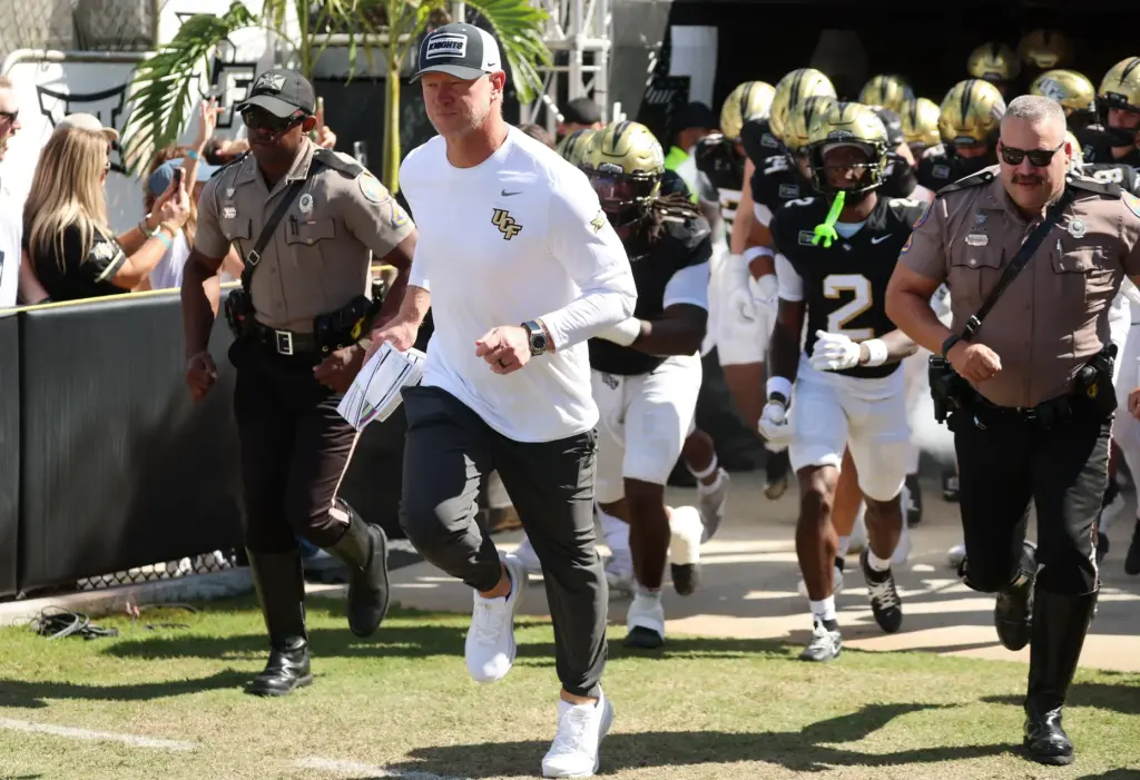 UCF coach Scott Frost leads players onto the field for...