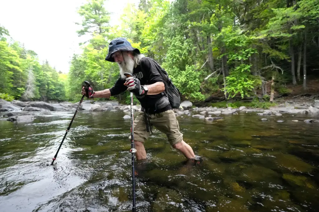 Appalachian Trail hiker Dale Sanders wades across Big Wilson Stream...