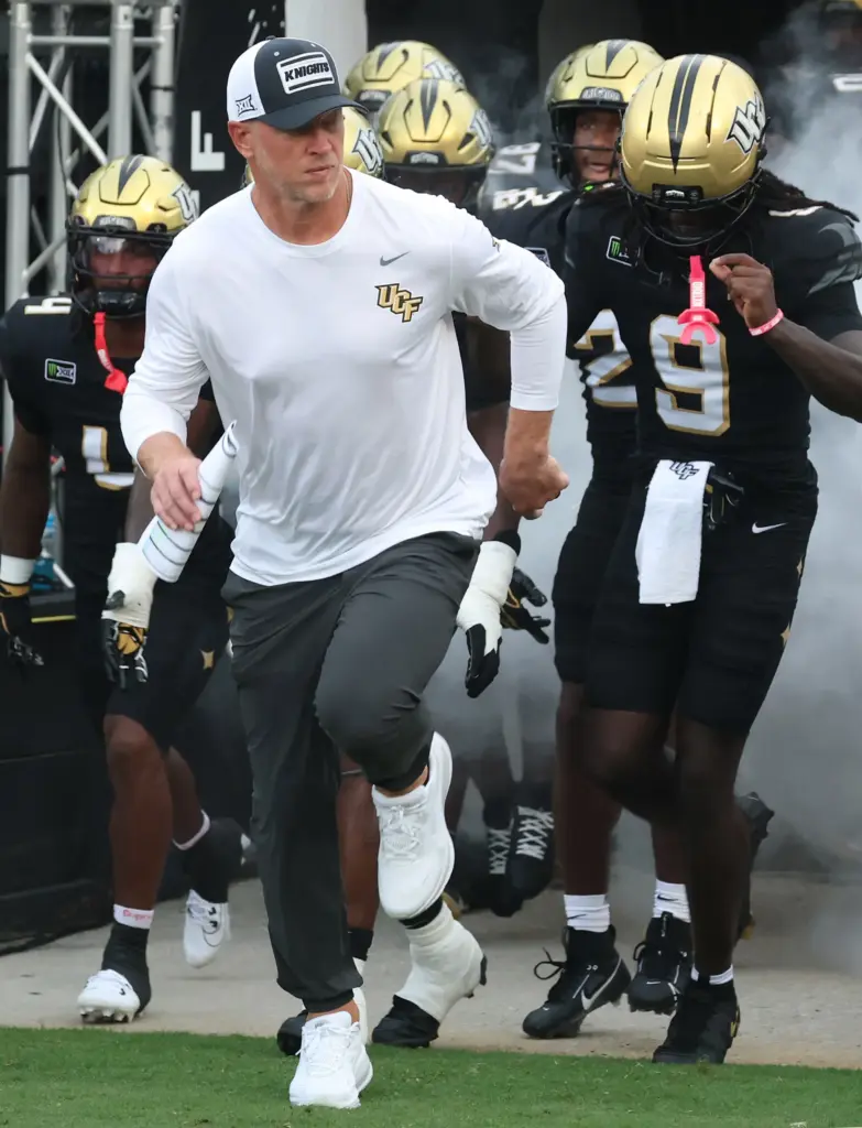 UCF coach Scott Frost leads players onto the field for...