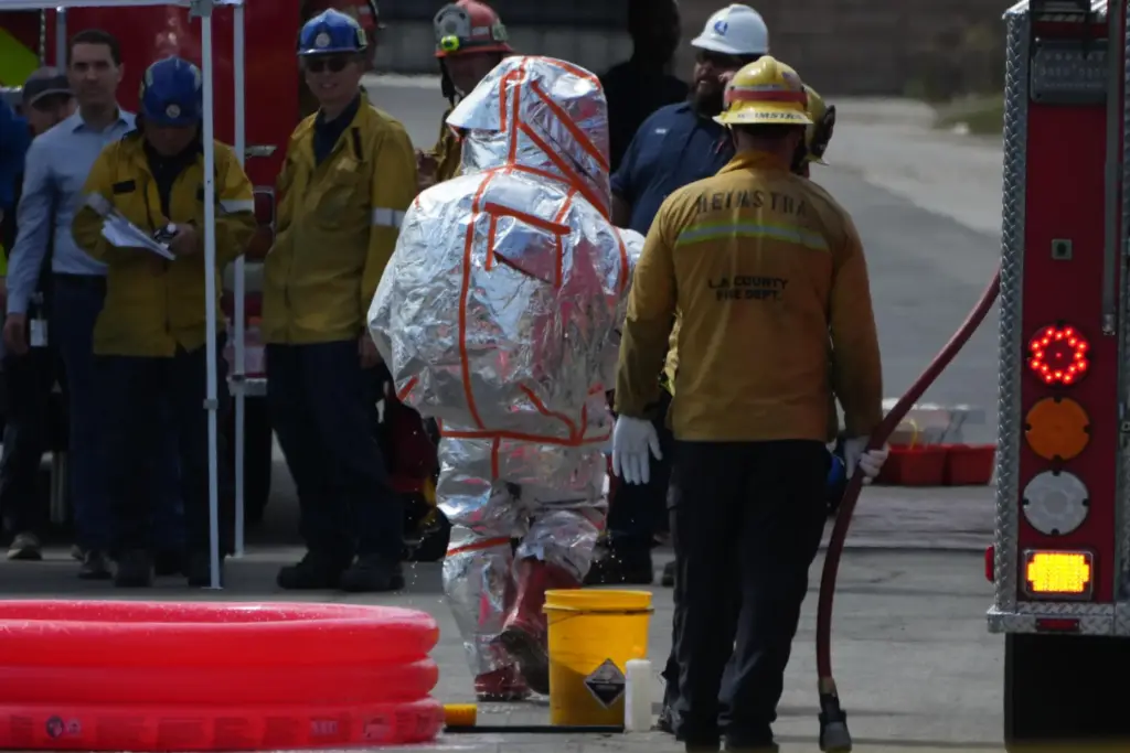 A fire fighter is assisted in removing his hazmat suit...