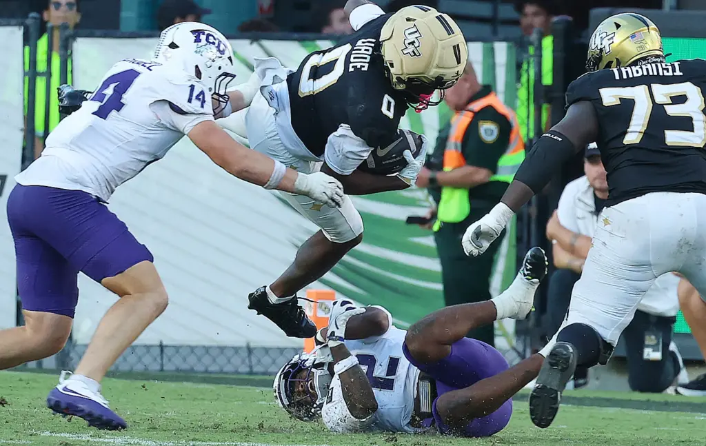 UCF tight end Dylan Wade (0) leaps over TCU defenders...
