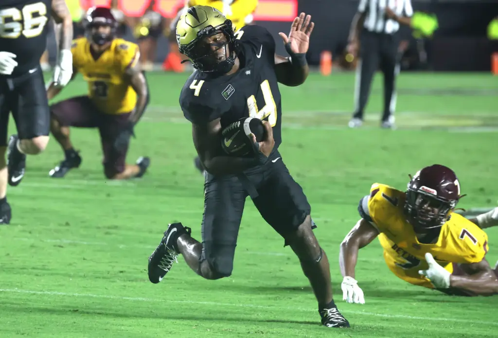 UCF running back Taevion Swint (4) dances away from defenders...