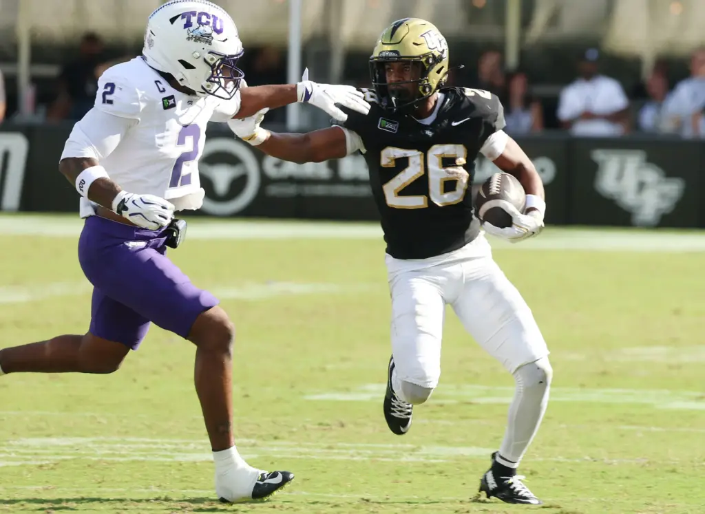 UCF running back Duke Watson (28) shoves aside TCU safety...