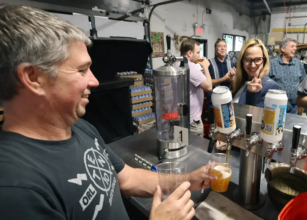 Brewery owner Mike Wallace, left, pulls a draft of cold...