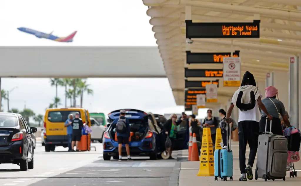 Travelers arrive for their flights, as a Southwest airliner takes...