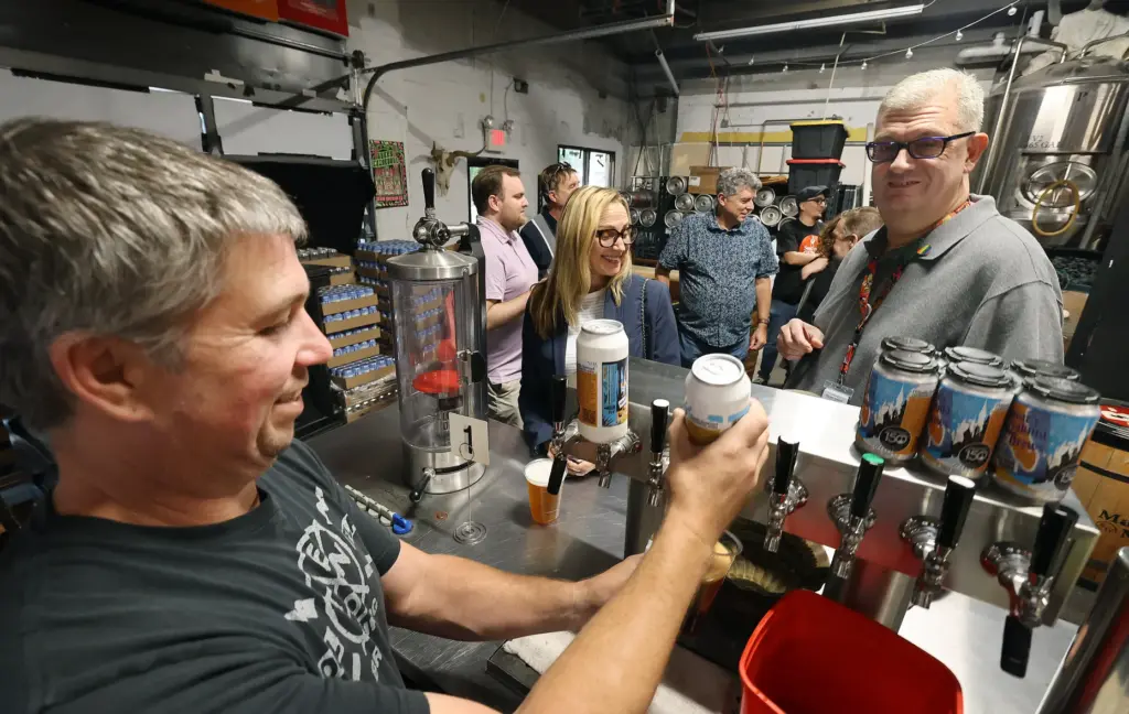 Brewery owner Mike Wallace, left, pulls a draft of beer...