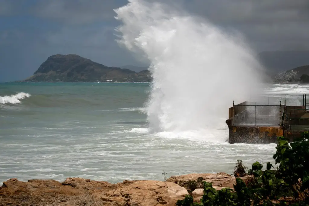 A large wave crashes on the shore caused by Hurricane...