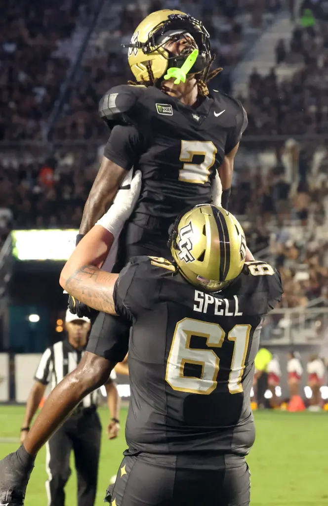 UCF offensive lineman Owen Spell (61) lifts wide receiver Jonathan...