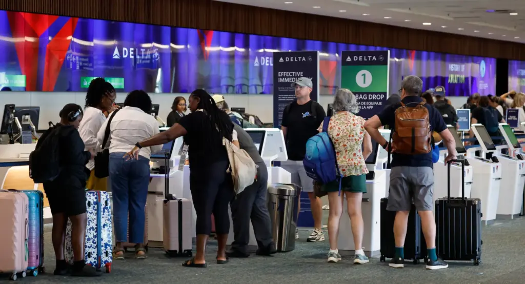 Travelers check in at the Delta Air Lines counter at...