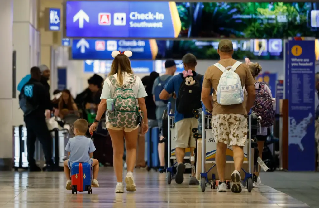 Travelers walk to their check-in counter at the Orlando International...