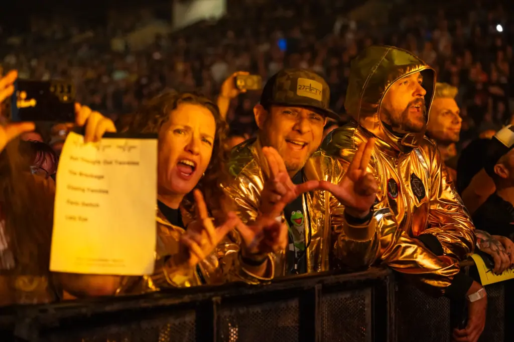 Weezer fans hold up the bandâs hand sign that forms...