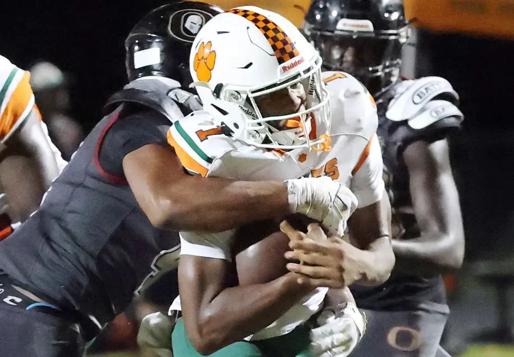 Jones High quarterback Peyton Carroll (1) runs through the3 tackle...