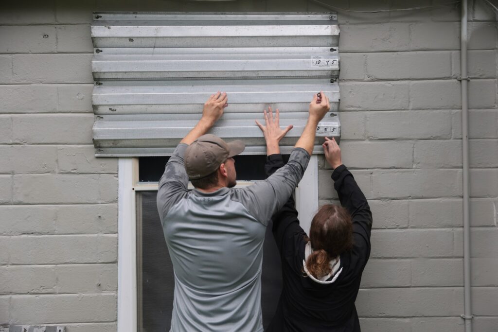 Dan Conley (L) and Suzanna Buchanan put up shutters before...