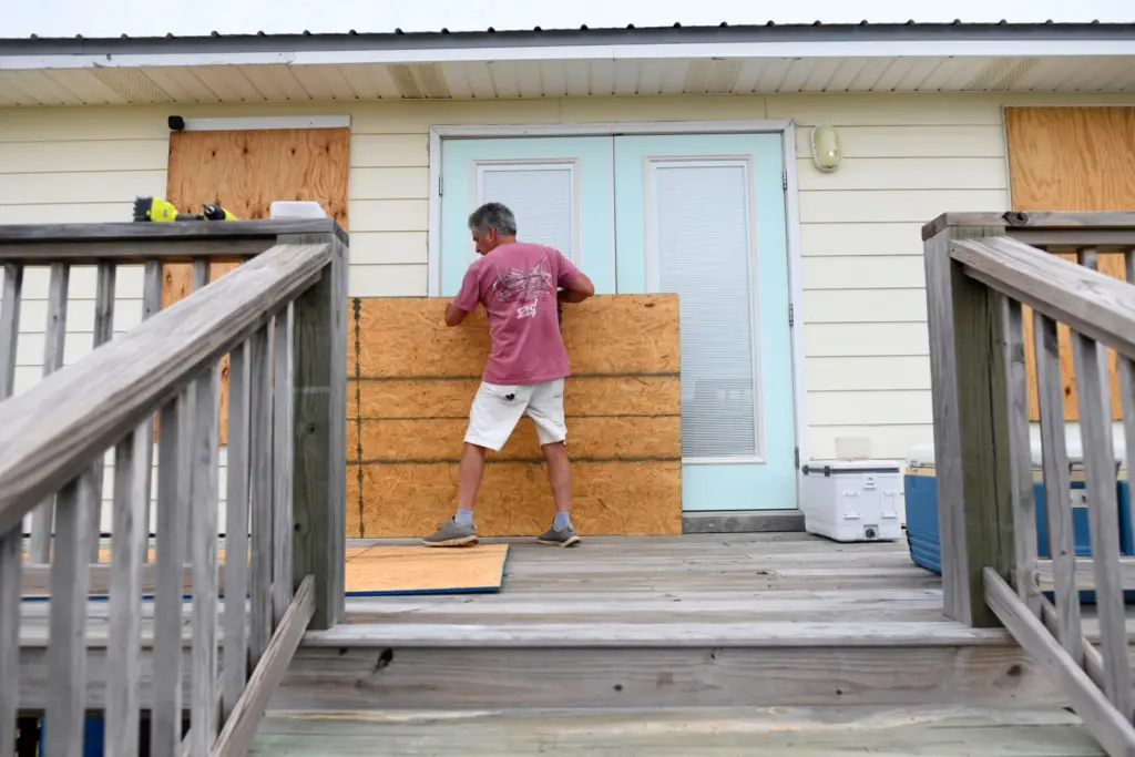 Larry Smith boards up his home with plywood ahead of...