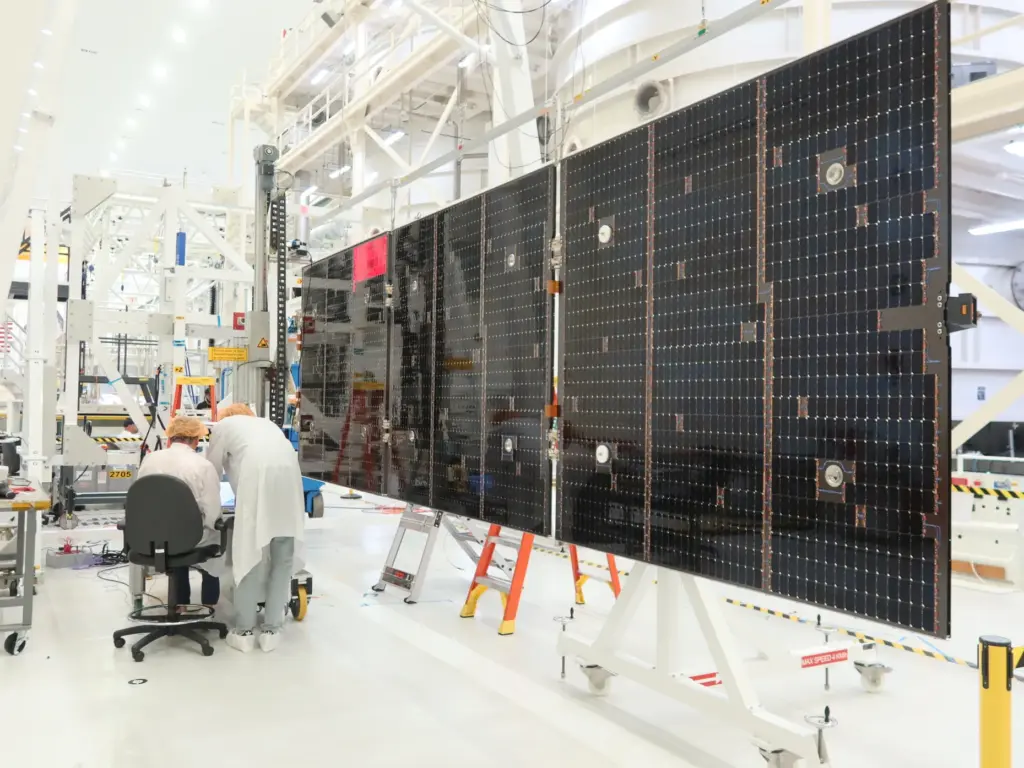 Technicians extend and inspect one of the solar array wing...